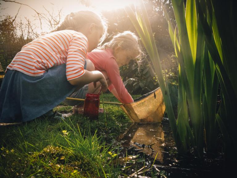 2 kinderen zoeken naar dieren in een vijvertje